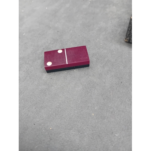 456 - A vintage cased set of red Bakelite and Catalin dominoes. The set features individual two-tone piece... 