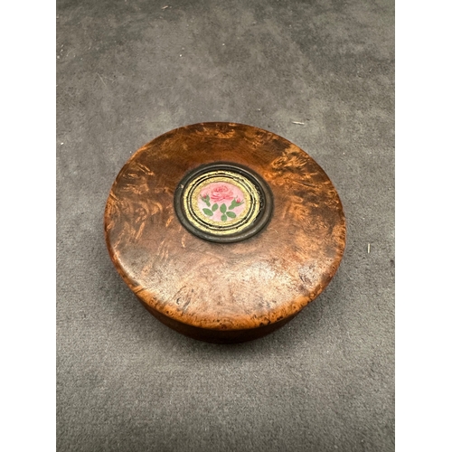 26 - A small, round burl wood box featuring a lift-off lid. The lid is adorned with a central circular me... 