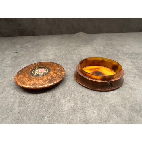 26 - A small, round burl wood box featuring a lift-off lid. The lid is adorned with a central circular me... 