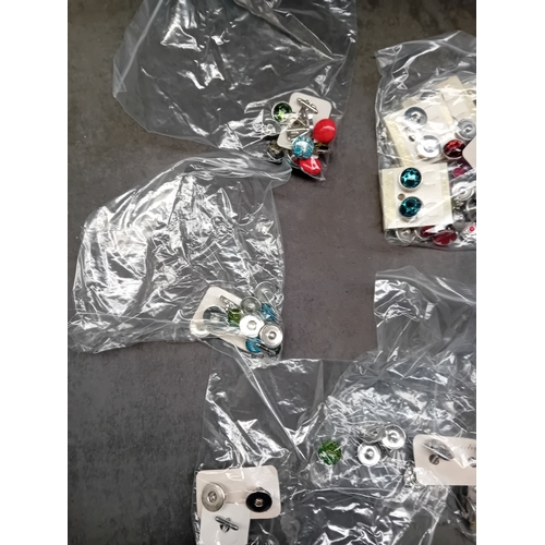 521 - A collection of five separate, sealed clear plastic bags containing assorted interchangeable snap bu... 