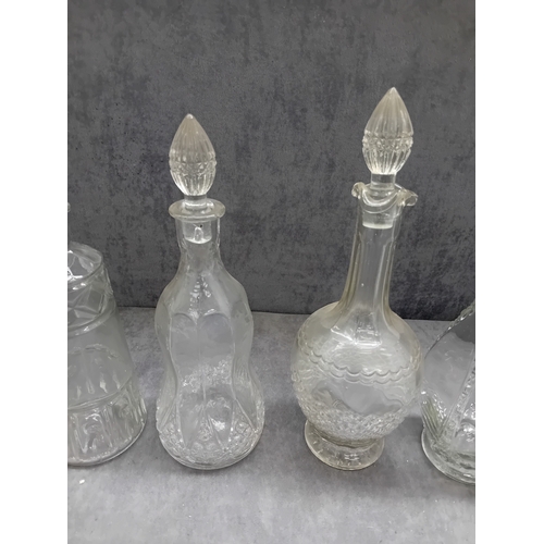583 - A collection of six clear glass decanters, each accompanied by a decorative stopper. The vessels exh... 