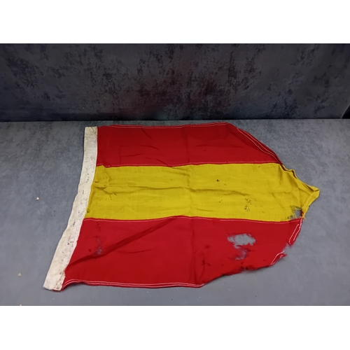 65 - A Spanish flag, featuring three horizontal stripes: red at the top, a wider yellow in the middle, an... 