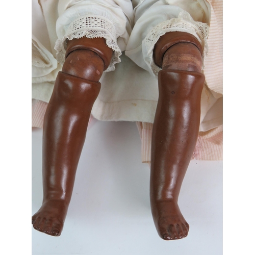 122 - An early 20th Century Bisque headed black girl doll with glass eyes and jointed arms and legs. Fully... 