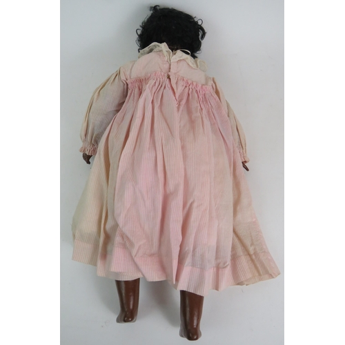 122 - An early 20th Century Bisque headed black girl doll with glass eyes and jointed arms and legs. Fully... 