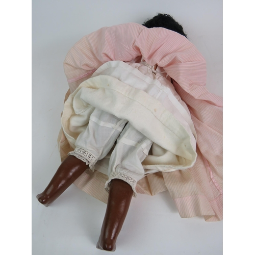 122 - An early 20th Century Bisque headed black girl doll with glass eyes and jointed arms and legs. Fully... 