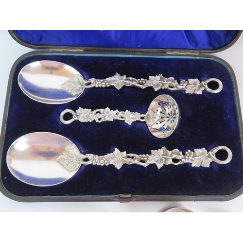 144 - A cased set of silver plated servers with cast grapevine handles plus 8 pieces of Egyptian white met... 