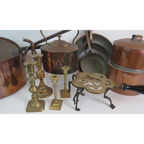 145 - Various copper and brass ware including candlesticks, a huge 19th Century sauce pans, trio of frying... 