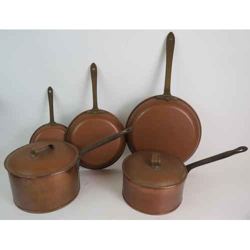 145 - Various copper and brass ware including candlesticks, a huge 19th Century sauce pans, trio of frying... 