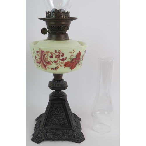 36 - A Victorian cast iron based oil lamp with hand decorated glass reservoir and spare chimney. Overall ... 