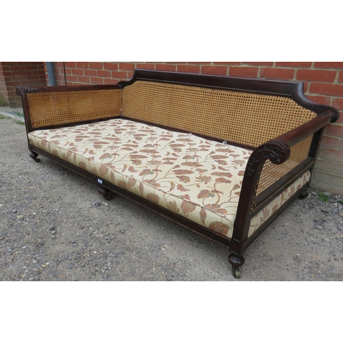 739 - A Victorian mahogany framed three seater bergere sofa with acanthus carved and scrolled armrests uph... 