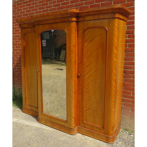 746 - A Victorian pale mahogany breakfront triple wardrobe with central mirrored door enclosing an arrange... 