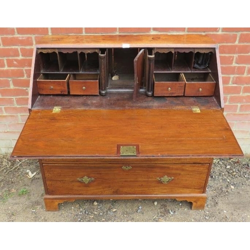 785 - A George III mahogany and oak bureau, the fall front enclosing an array of small drawers and cubby h... 