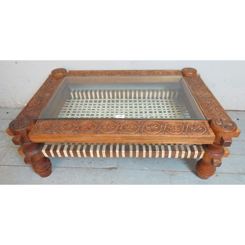 789 - A vintage Ethiopian hardwood low coffee table with inset glass top set within an ornately carved bor... 