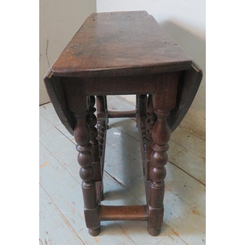 790 - A late 17th century oak gate leg table, raised on a ball turned base, united by lower stretchers ter... 