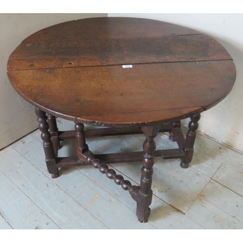 790 - A late 17th century oak gate leg table, raised on a ball turned base, united by lower stretchers ter... 