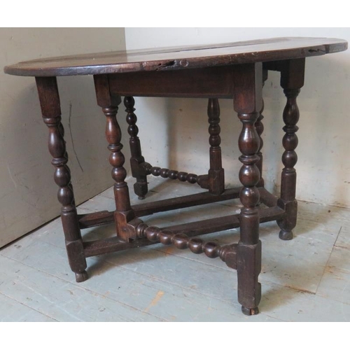 790 - A late 17th century oak gate leg table, raised on a ball turned base, united by lower stretchers ter... 