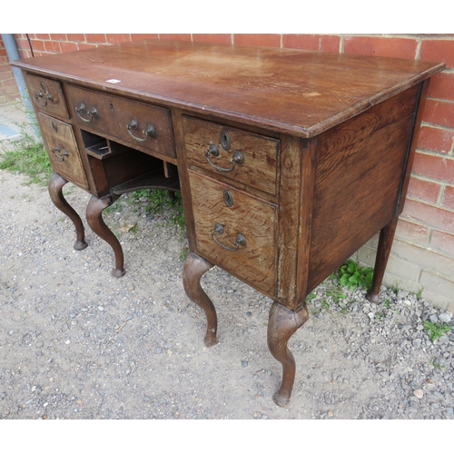 796 - A Georgian oak kneehole desk having a configuration of five drawers, fitted with brass bail handles ... 