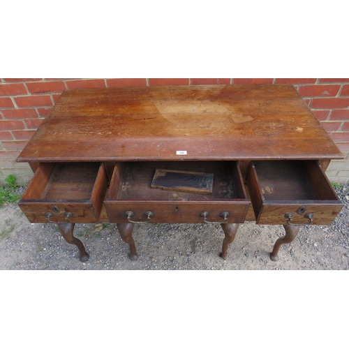 796 - A Georgian oak kneehole desk having a configuration of five drawers, fitted with brass bail handles ... 