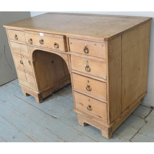 808 - An antique pine kneehole desk, the base having an arrange of six drawers and a cupboard to one side ... 