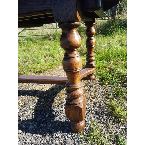 833 - A good quality reproduction extending oak dining table with two extra leaves raised on baluster supp... 