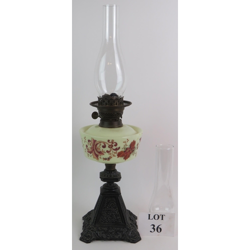 36 - A Victorian cast iron based oil lamp with hand decorated glass reservoir and spare chimney. Overall ... 