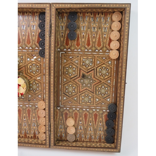 91 - An inlaid Damascus Ware games box with backgammon board interior and chess board exterior. Bone coun... 