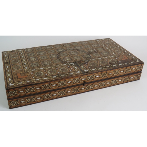 91 - An inlaid Damascus Ware games box with backgammon board interior and chess board exterior. Bone coun... 