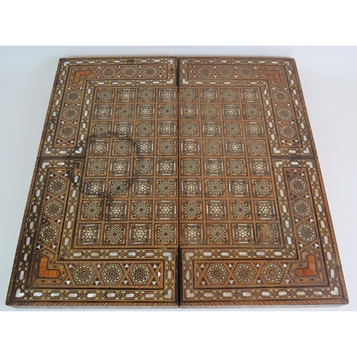 91 - An inlaid Damascus Ware games box with backgammon board interior and chess board exterior. Bone coun... 