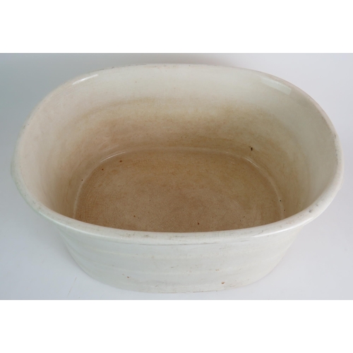 99 - A large antique glazed cream pottery footbath. 49cm x 32cm x 22cm. Condition report: Overall crazing... 