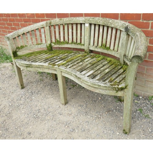 842 - A nicely weathered teak garden bench with a shaped front and slatted seat & back rests, raised on ba... 