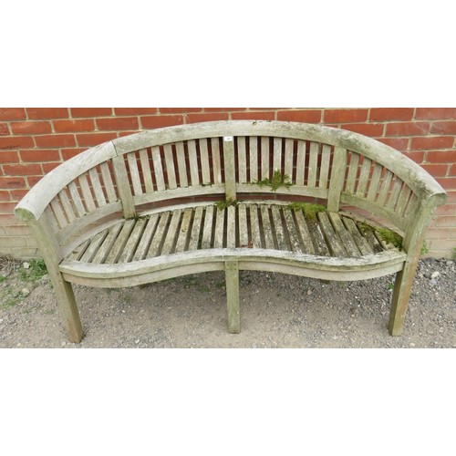 843 - A nicely weathered teak garden bench with a shaped front and slatted seat & back rests, raised on ba... 