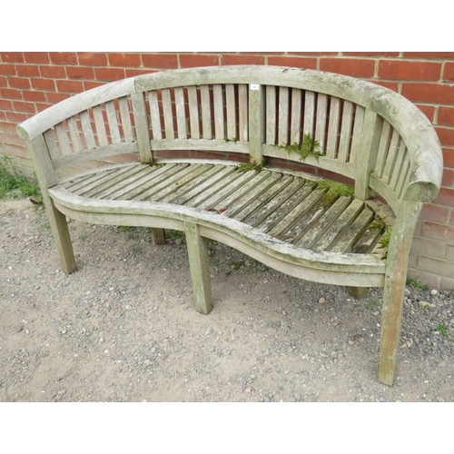 843 - A nicely weathered teak garden bench with a shaped front and slatted seat & back rests, raised on ba... 