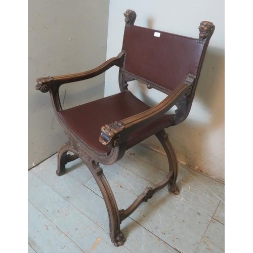 773 - A vintage mahogany Savonarola chair ornately carved with grotesque mask finials & armrests, raised o... 