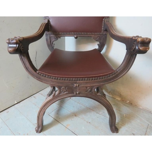 773 - A vintage mahogany Savonarola chair ornately carved with grotesque mask finials & armrests, raised o... 