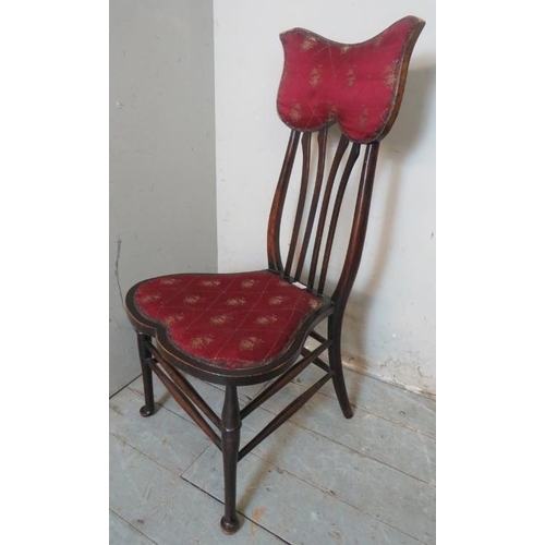 776 - An Art Nouveau occasional chair with unusually shaped back rest and seat upholstered in claret gold ... 