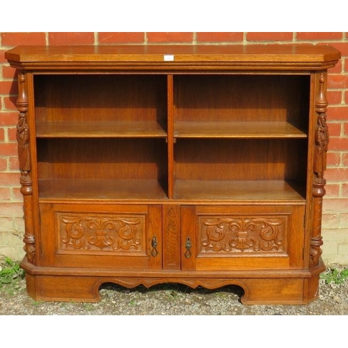 782 - A vintage carved oak low open bookcase comprising four shelves over a cupboard base flanked by a pai... 