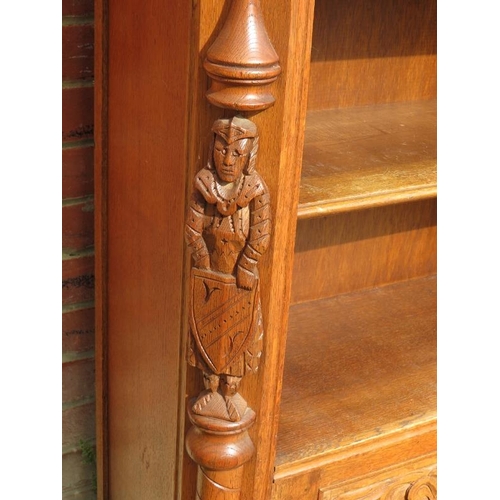 782 - A vintage carved oak low open bookcase comprising four shelves over a cupboard base flanked by a pai... 