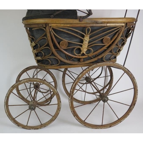 117 - A Victorian style doll's pram with rattan cane basket. Steel frame, porcelain handles and wood frame... 