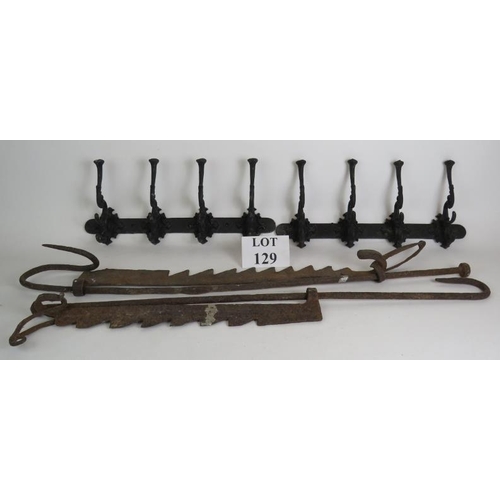 129 - Two ornate cast iron coat racks, both 45cm long, plus two old iron fire trammel pot hangers. (4).
Co... 