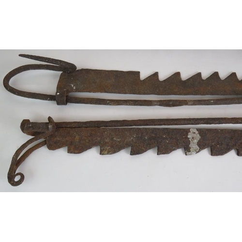 129 - Two ornate cast iron coat racks, both 45cm long, plus two old iron fire trammel pot hangers. (4).
Co... 