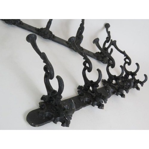 129 - Two ornate cast iron coat racks, both 45cm long, plus two old iron fire trammel pot hangers. (4).
Co... 