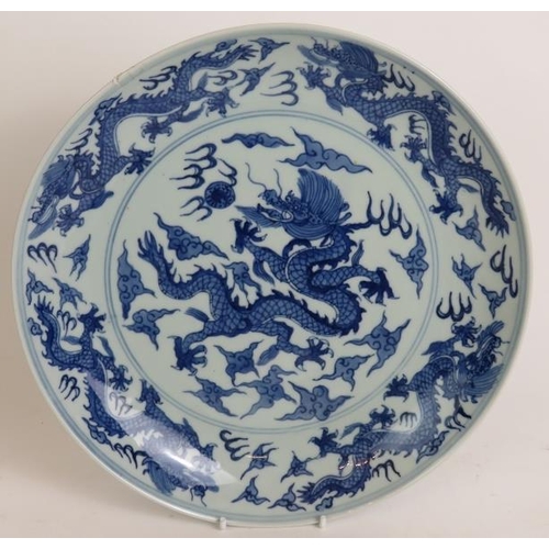 15 - An antique Chinese porcelain blue and white charger depicting a pearl chasing dragon within a four d... 