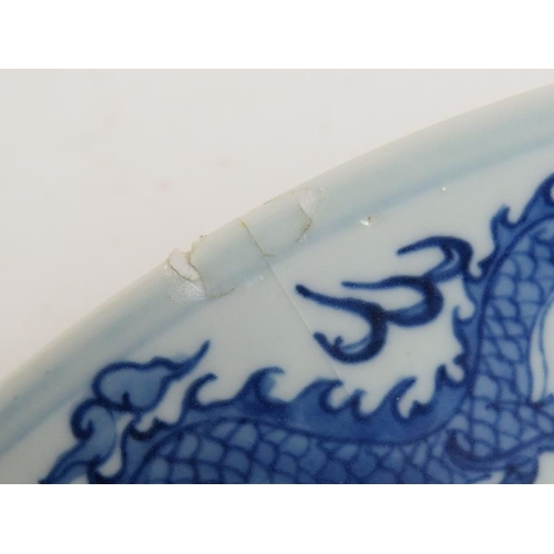 15 - An antique Chinese porcelain blue and white charger depicting a pearl chasing dragon within a four d... 