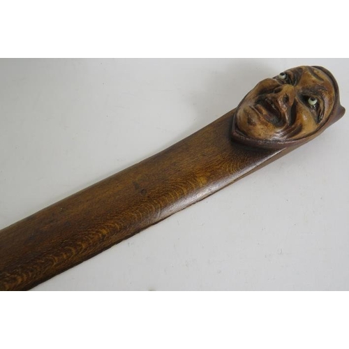 151 - A late 19th/early 20th Century carved wood page turner with mask finial of a demonic figure with gla... 