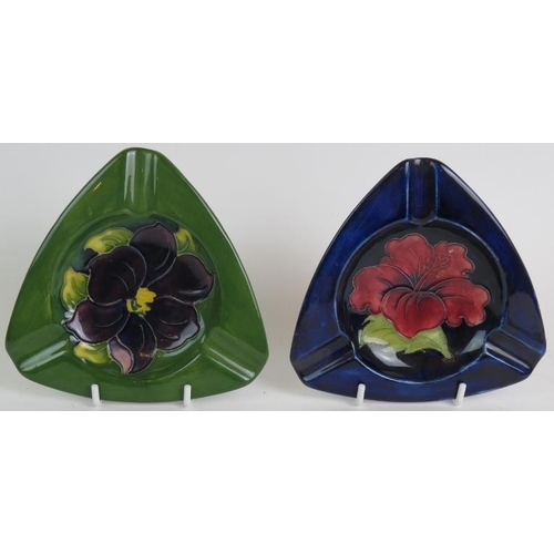 53 - A Moorcroft pottery hibiscus pattern table lighter and two similar triangular ash trays, one bearing... 