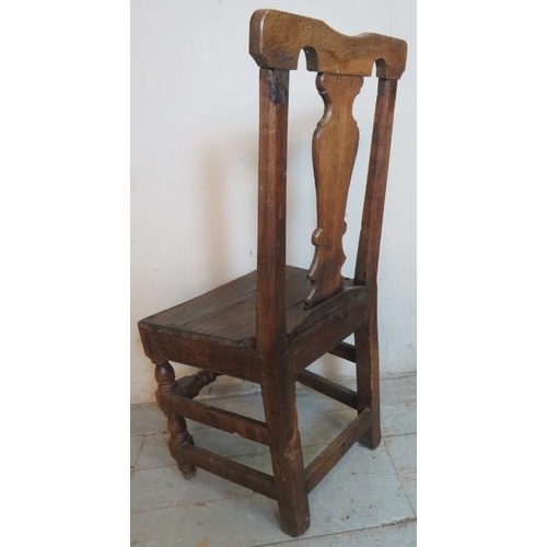 709 - An early 18th century oak hall chair of immense character featuring a shaped back splat, raised on t... 