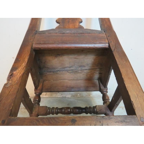 709 - An early 18th century oak hall chair of immense character featuring a shaped back splat, raised on t... 