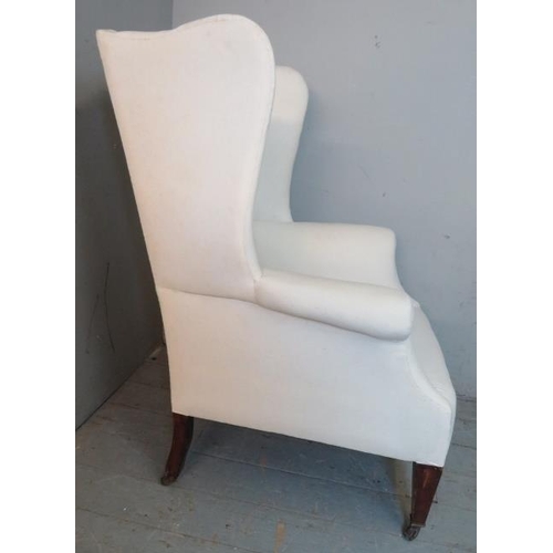 712 - An antique wingback armchair in the Queen Anne style, upholstered in calico and raised on tapering s... 