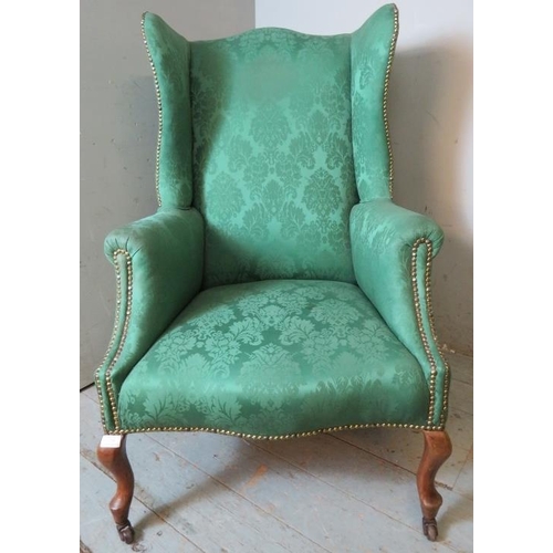 719 - A 19th century wingback armchair upholstered in sage green damask fabric, raised on fruitwood cabrio... 