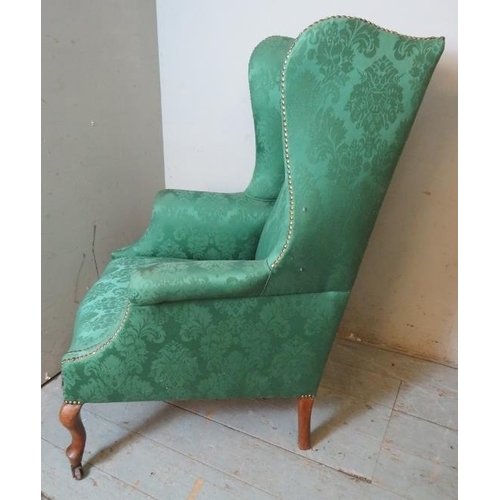 719 - A 19th century wingback armchair upholstered in sage green damask fabric, raised on fruitwood cabrio... 